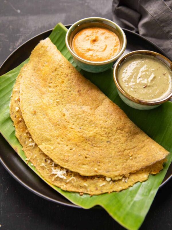 High Protein Dosa served on a banana leaf with chutney and curry on the side