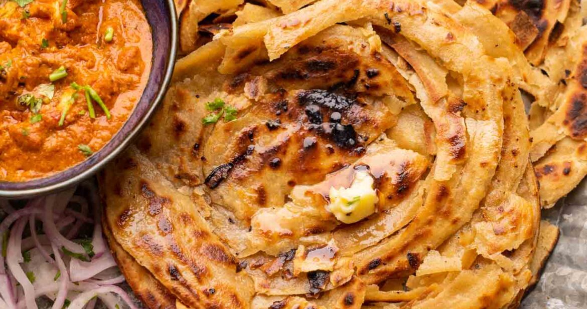 Lachha Parathas served on a plate with curry and onions