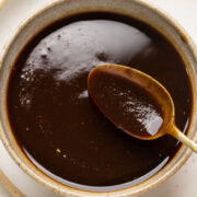 A spoonful of tamarind chutney being taken out of a bowl