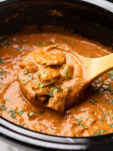 A shot of a ladle-full of chicken tikka masala in a slow cooker