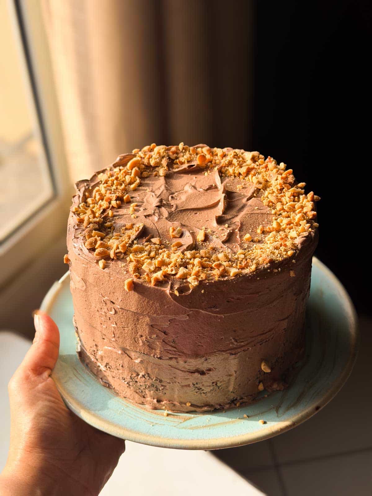 an image of the whole chocolate cake decorated with frosting and crushed nuts