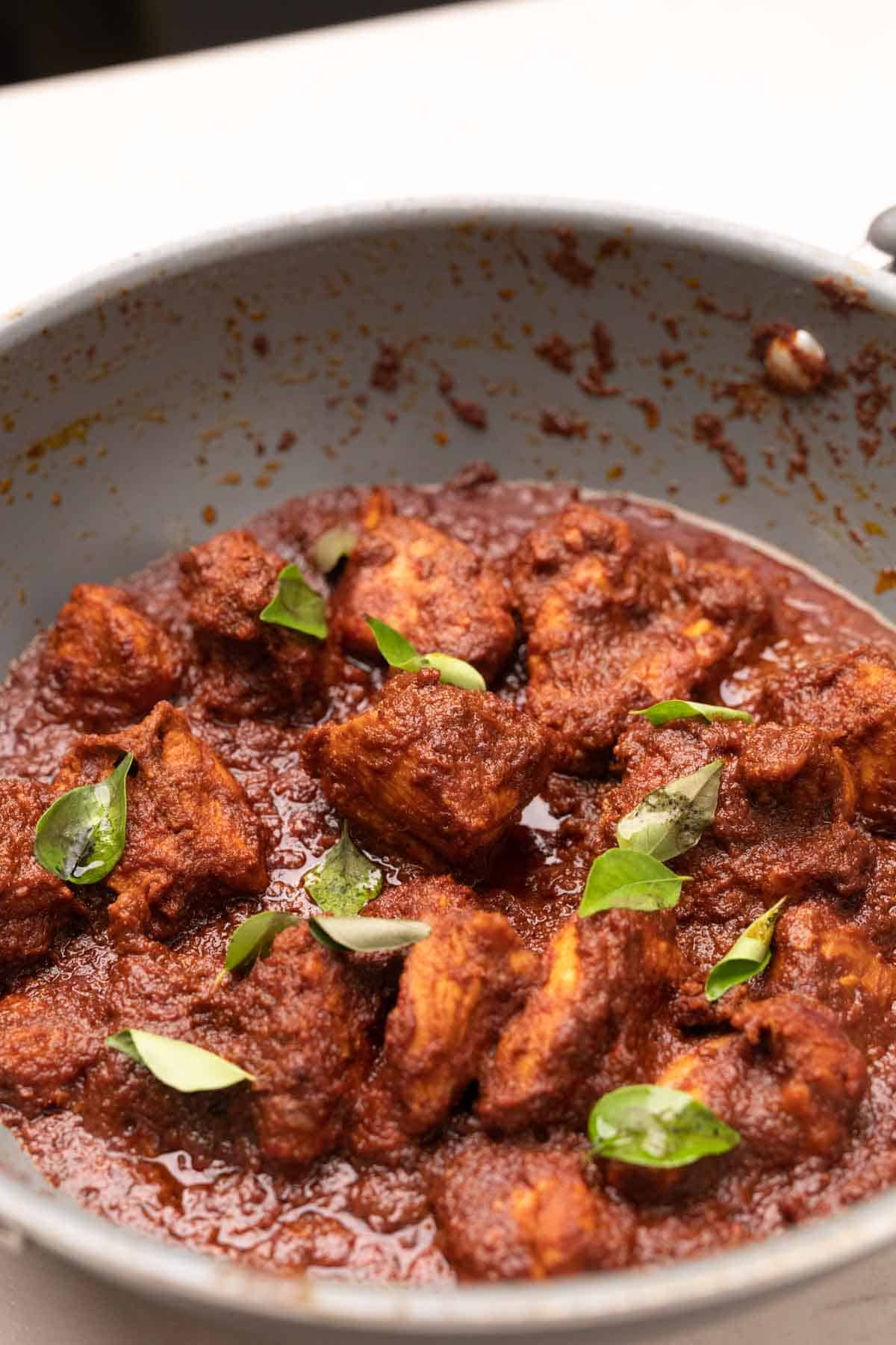 chicken ghee roast being cooked in a grey pan