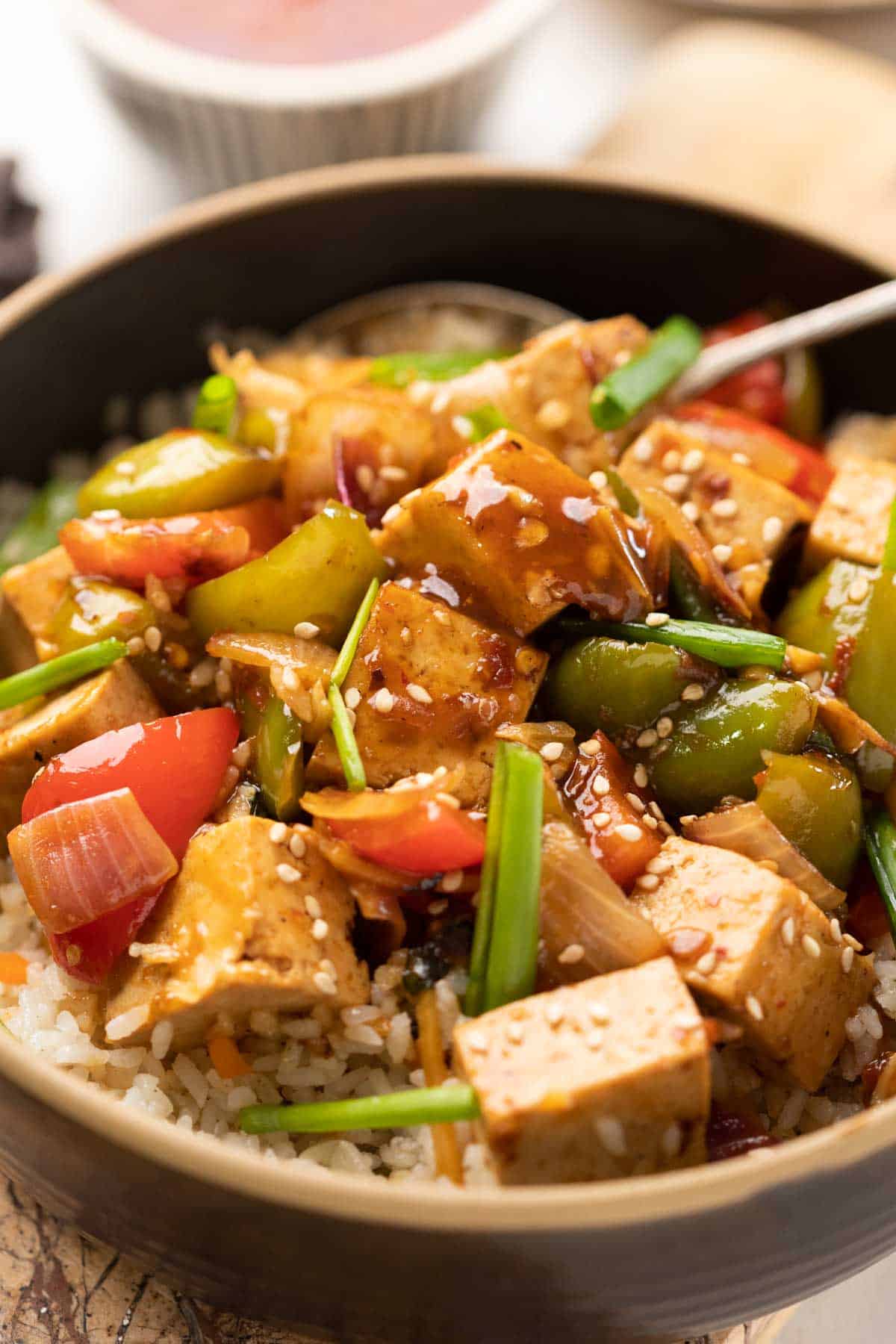 Sweet Chili Tofu Stir Fry served over rice in a bowl.