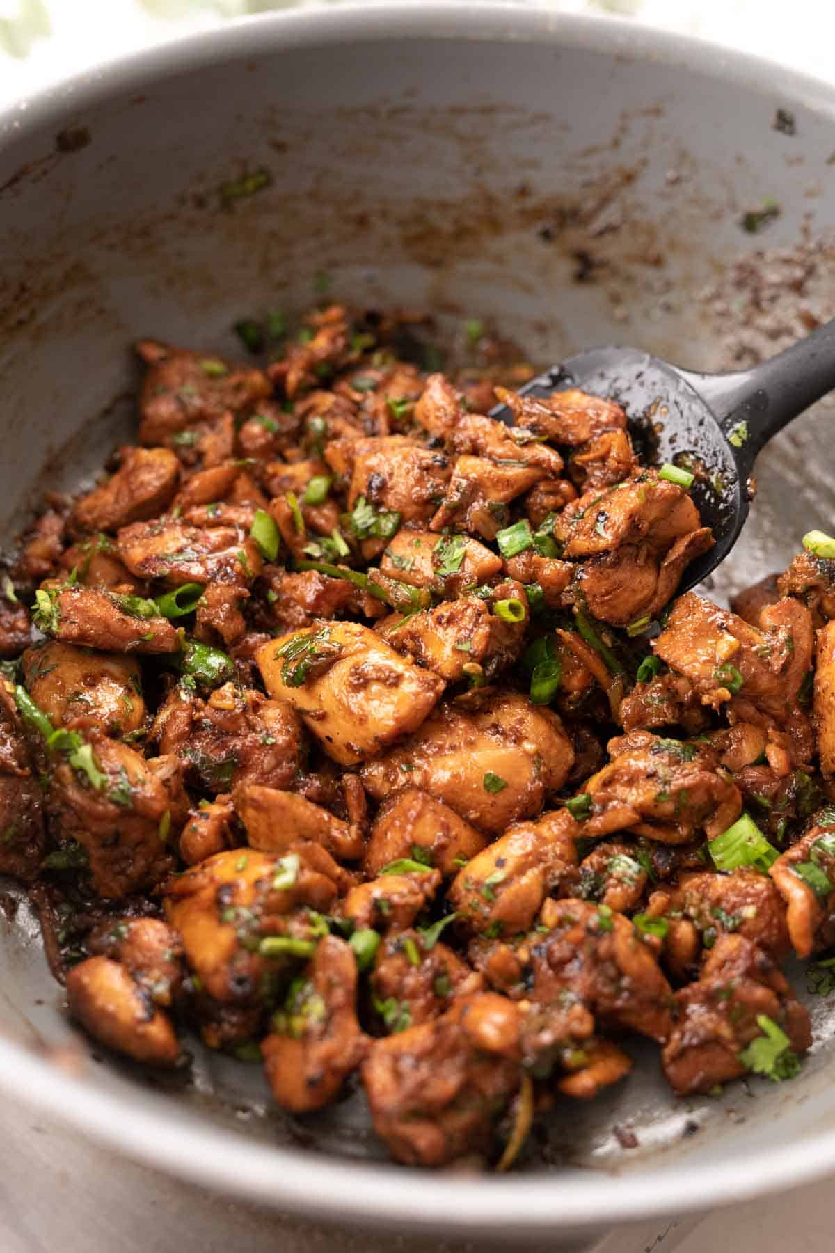 shot of ginger chicken in pan topped with spring onions