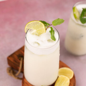 glass with limonada with a sprig of mint and slices of lemon on the side