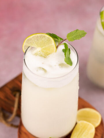 glass with limonada with a sprig of mint and slices of lemon on the side