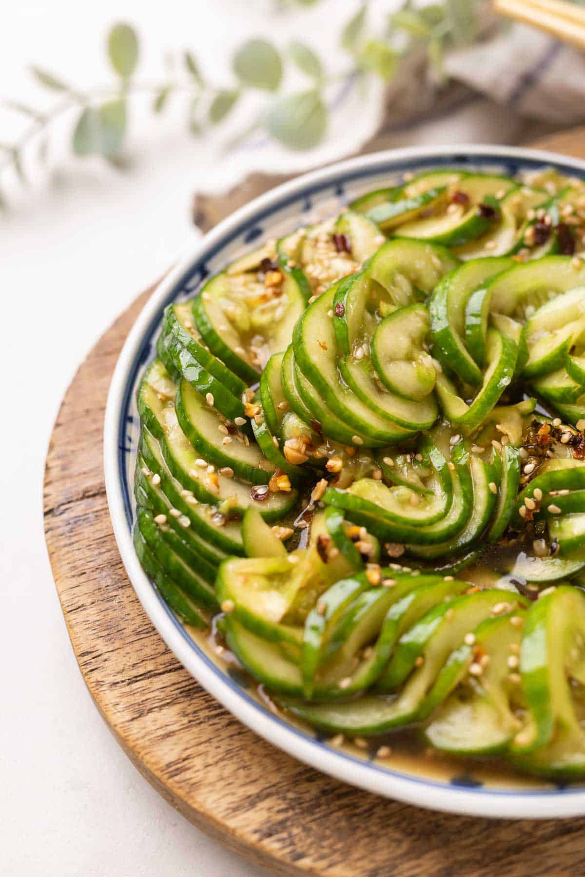 asian cucumber salad served in a blue and white plate placed on a brown board