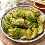 Asian cucumber salad served on a vibrant white and undecorous plate, featuring sliced Persian cucumbers tossed in a flavourful dressing