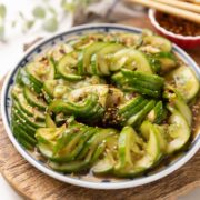 Asian cucumber salad served on a vibrant white and blue plate, featuring sliced Persian cucumbers tossed in a flavourful dressing