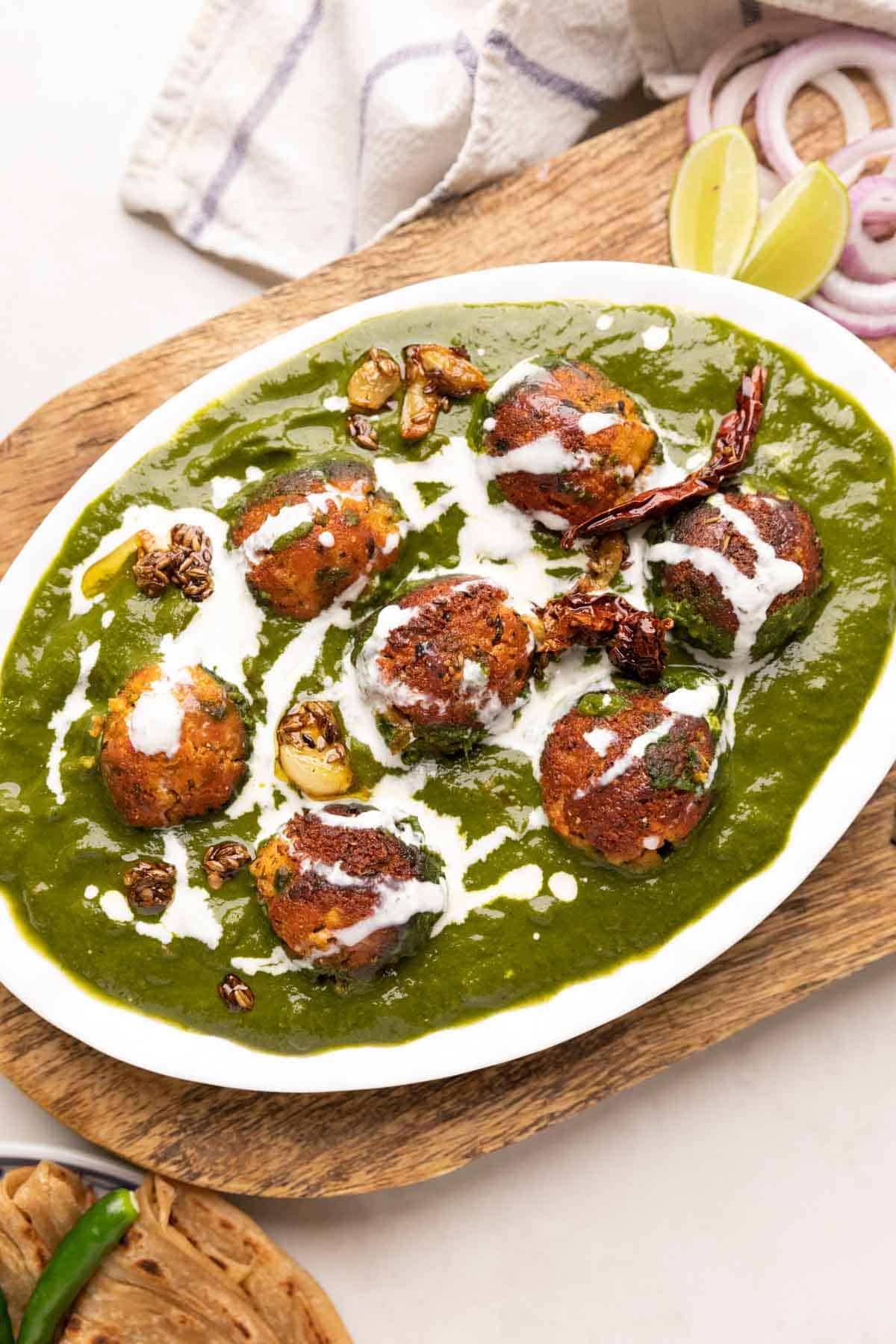 The Healthy Palak Paneer Kofta Curry in a dishj with cream drizzled on top