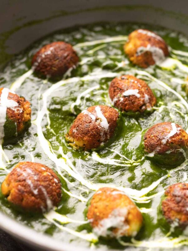 The Healthy Palak Paneer Kofta Curry in a pan with cream drizzled on top