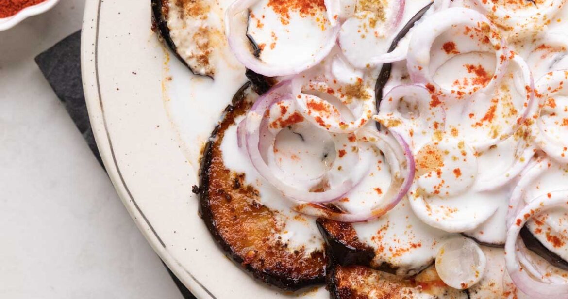 platter with fried eggplant slices and sliced onion topped with a curd mix