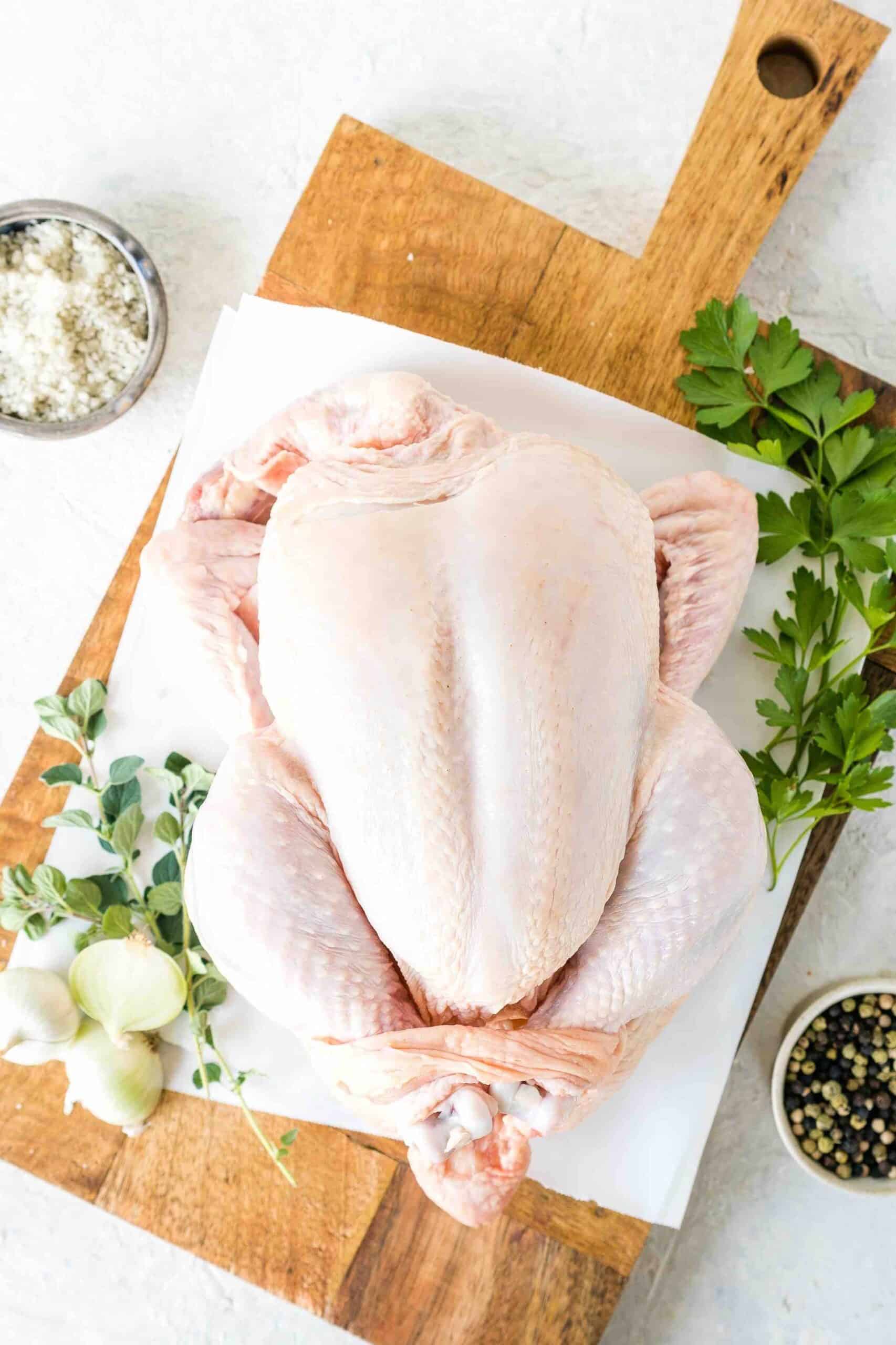 image of whole chicken with skin on a chopping board with accompaniments on the side