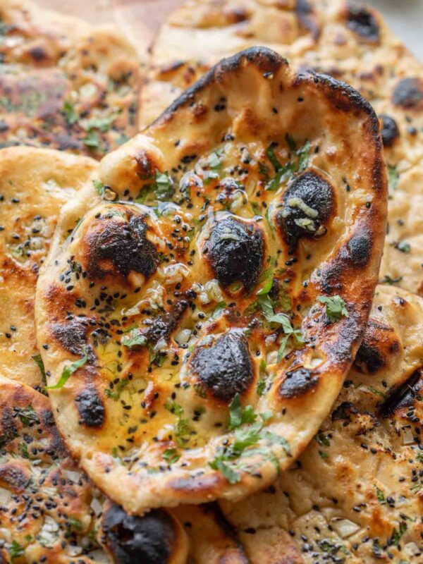 close up image of butter garlic naan stacked one on top of the other