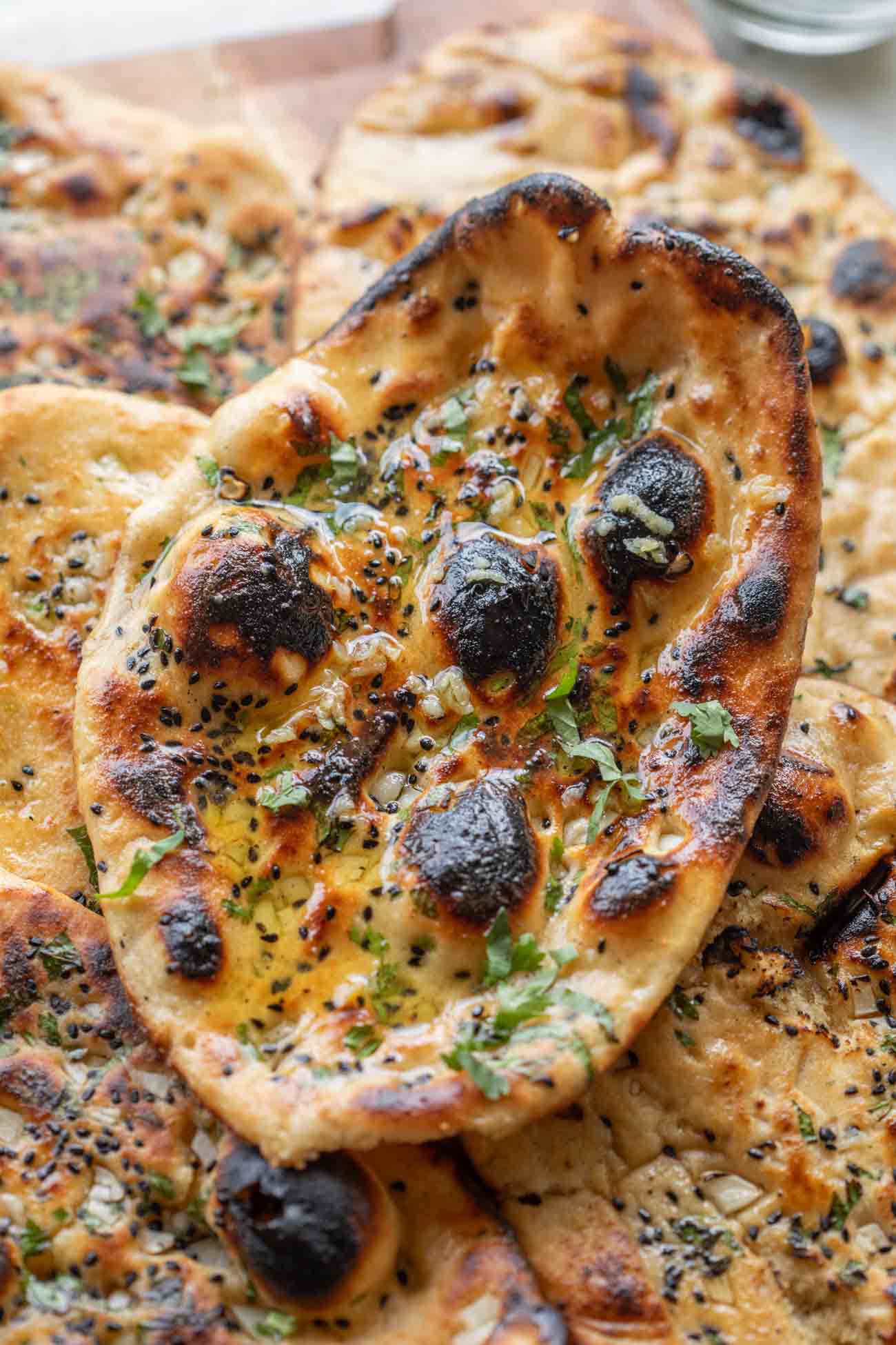 close up image of butter garlic naan stacked one on top of the other 