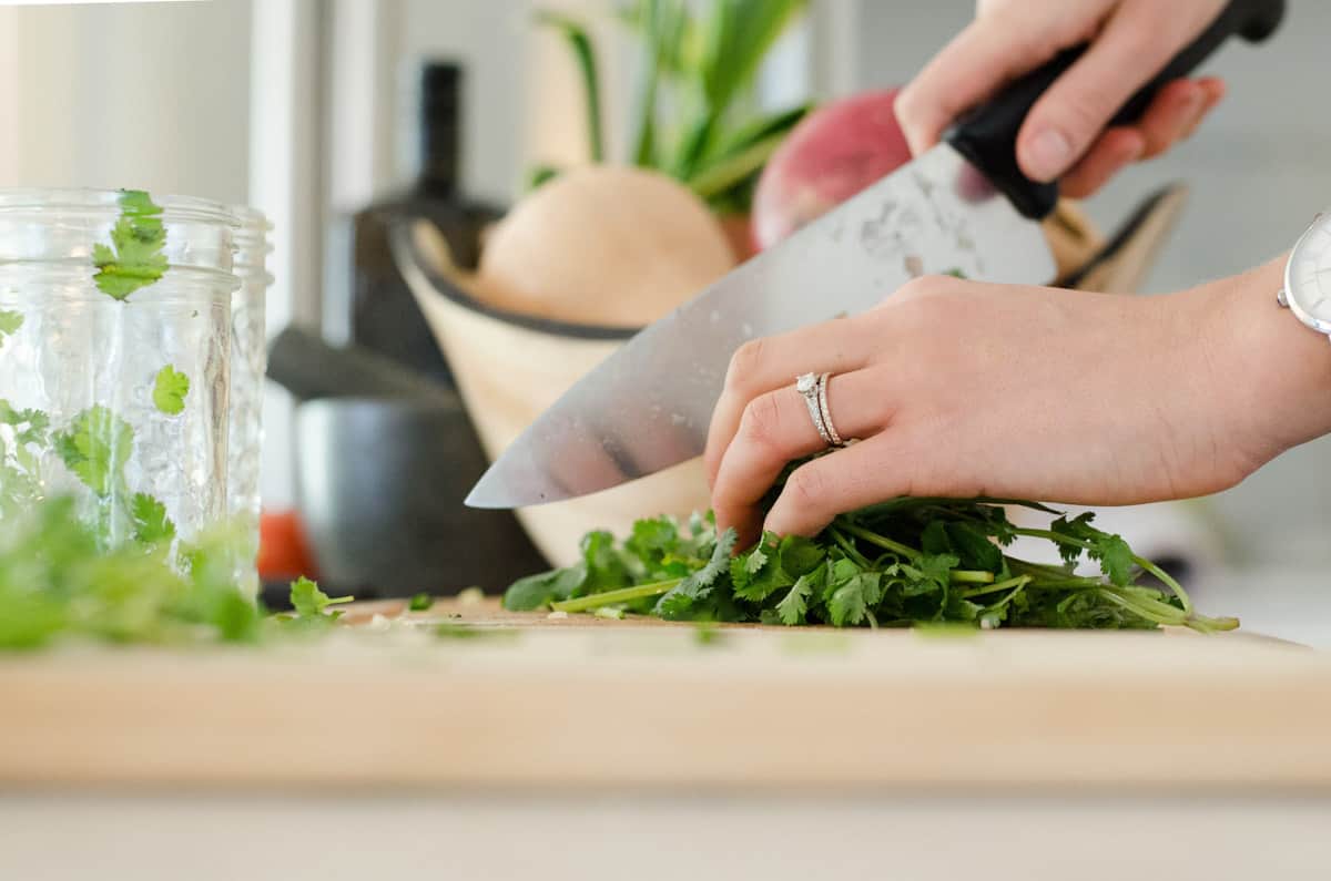 shot of fresh herbs being cut on a wooden chopping board