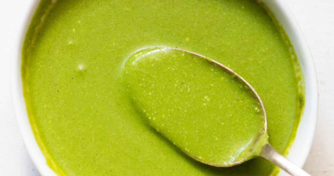 mint chutney served in a white bowl with a spoonful of chutney being taken out