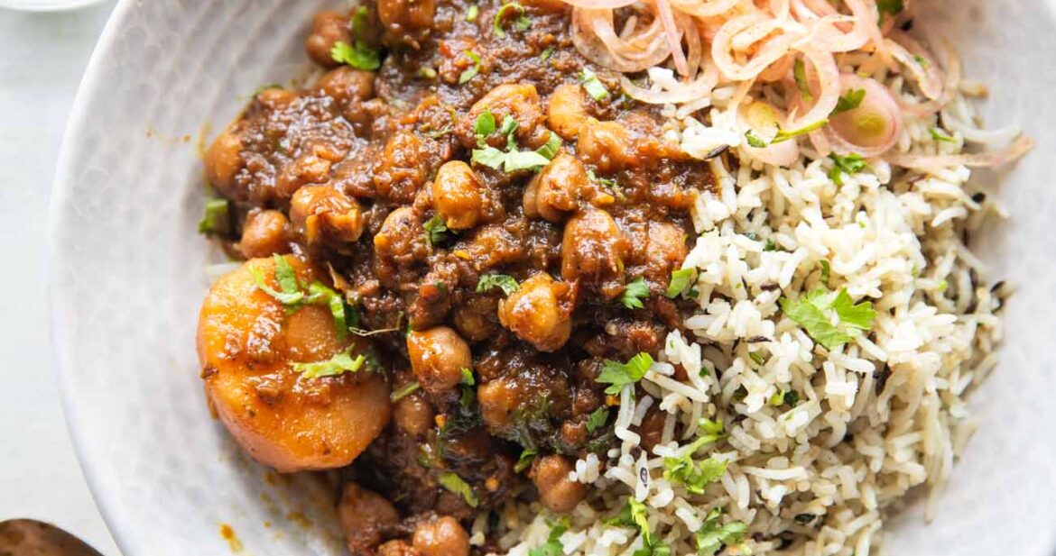 Pressure cooker chana masala served in a bowl with rice and onions on the side
