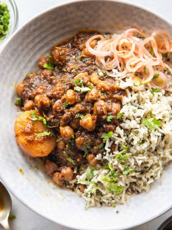 Pressure cooker chana masala served in a bowl with rice and onions on the side