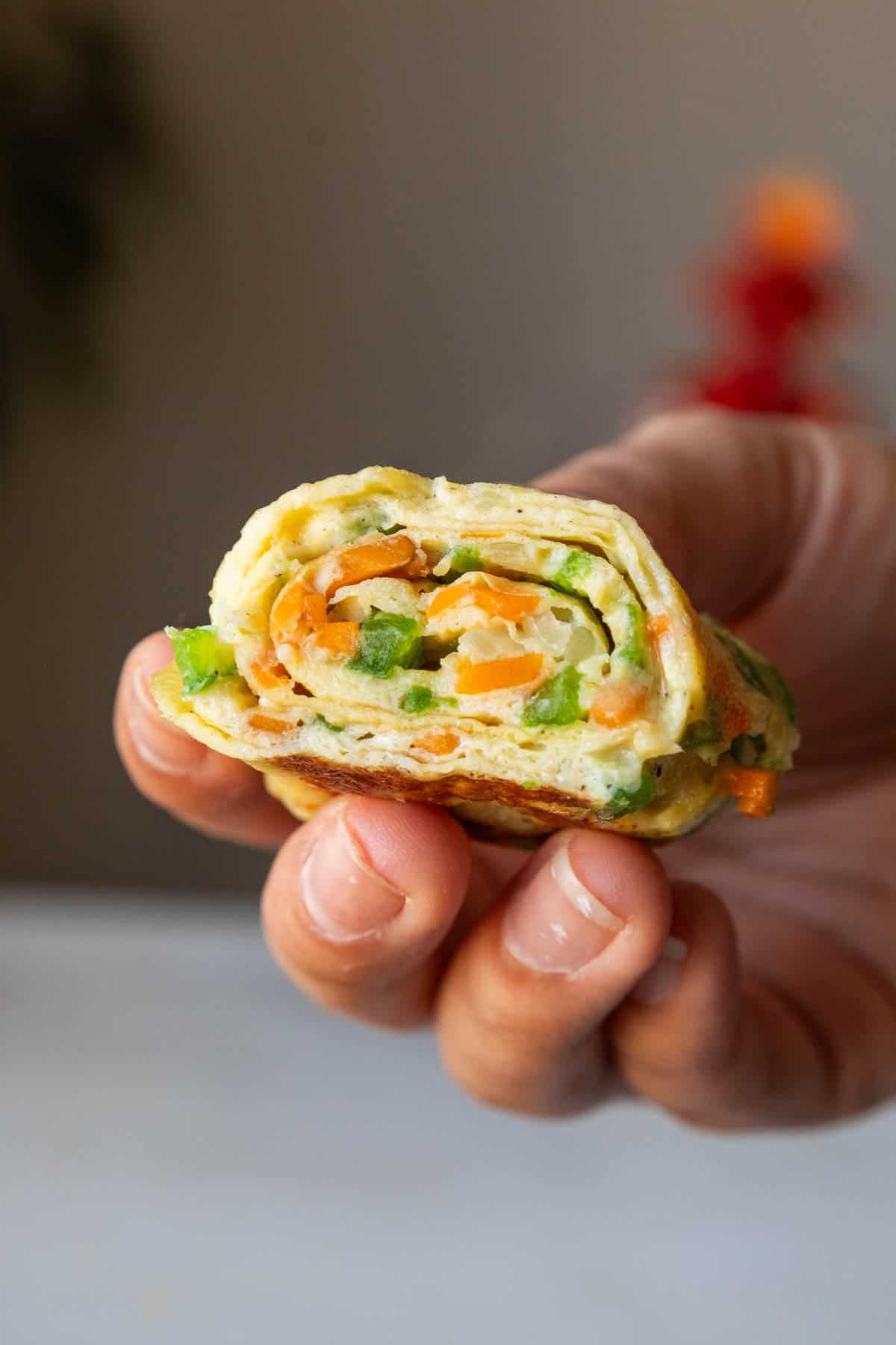 a close up shot of korean omelette roll being held in a hand