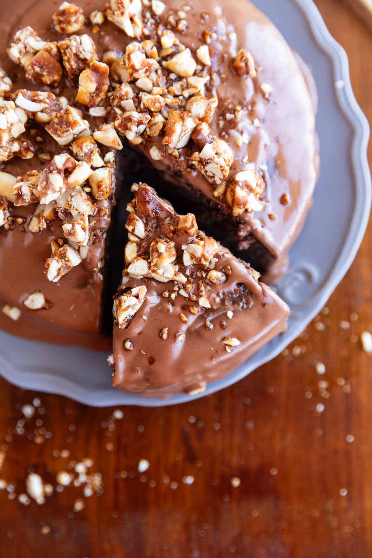 ragi chocolate cake with frosting and nuts sprinkled on top on a grey plate