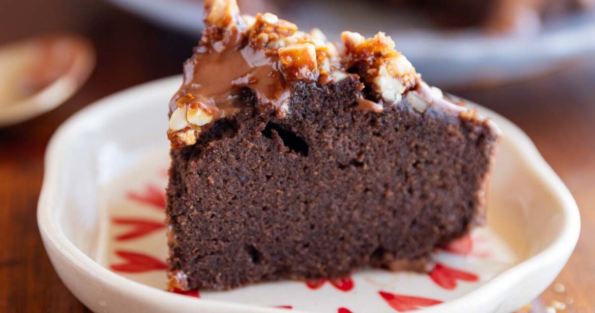 slice of ragi chocolate cake on a white plate with nuts sprinkled on top