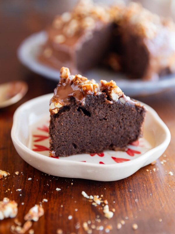 slice of ragi chocolate cake on a white plate with nuts sprinkled on top