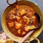 Bihari chicken curry served in a kadhai with roti and onions on the side