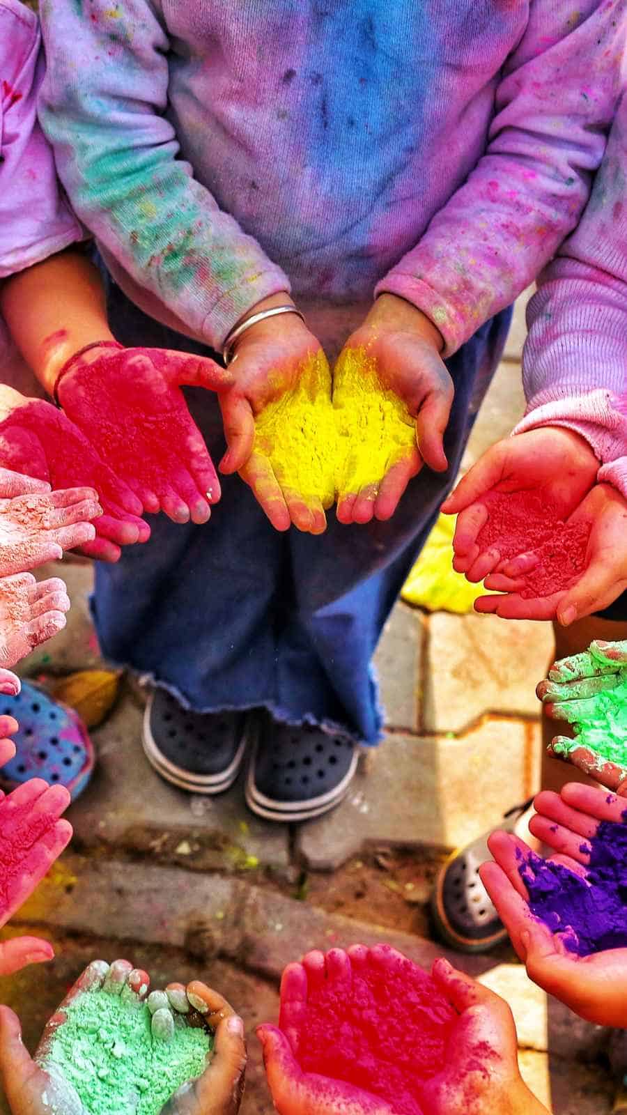 a picture of kids holding holi colours in their hands standing in a circle
