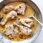 rezala chicken curry in a aluminium kadhai along with a spoon