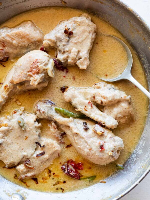 rezala chicken curry in a aluminium kadhai along with a spoon