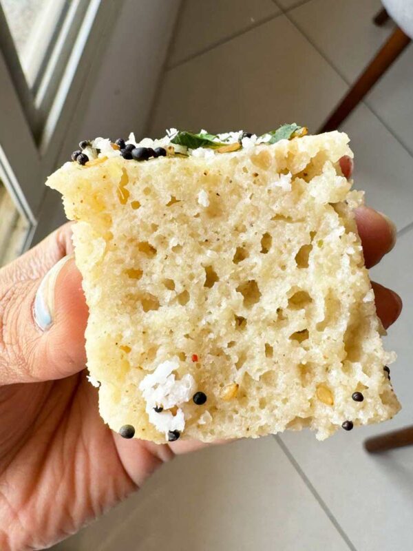 Close up of a piece of jowar dhokla to show the spongy and airy texture of the dhokla