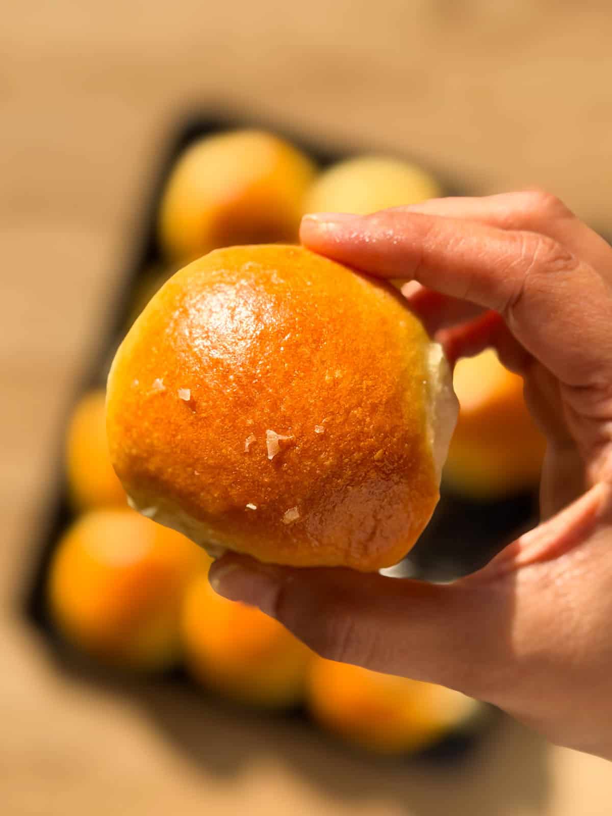 a person holding an air fryer dinner roll to showcase it's golden exterior
