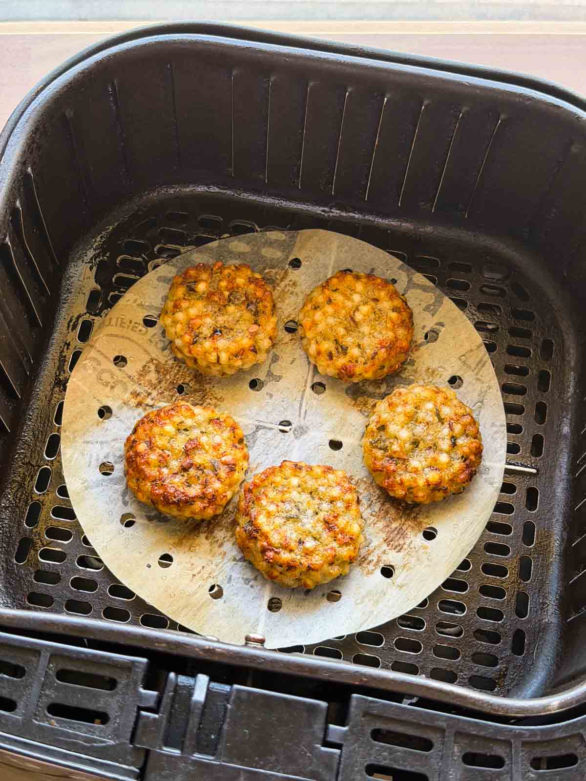 Crisp and cooked golden brown sabudana vadas shown in the air fryer basket