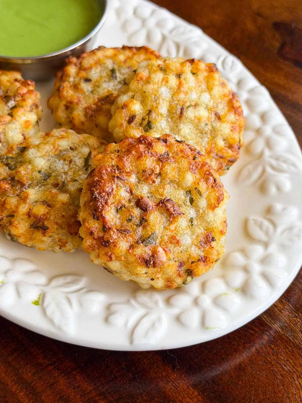 Crispy crunchy golden brown sabudana vadas served on a white platter with green mint chutney