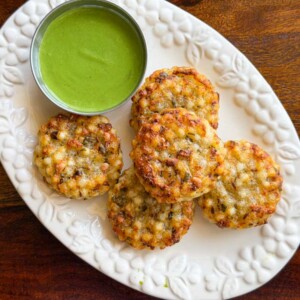 Crispy crunchy golden brown sabudana vadas served on a white platter with green mint chutney