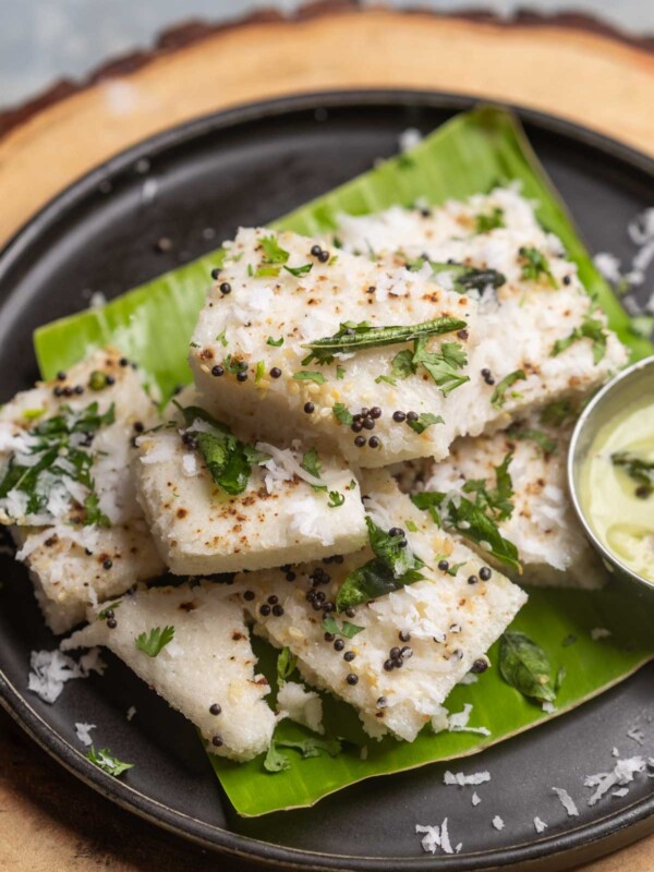 white dhokla served on a banana leaf platter with chutney
