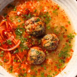 close up image of air fryer chicken meatballs in ginger broth to showcase it's texture and color