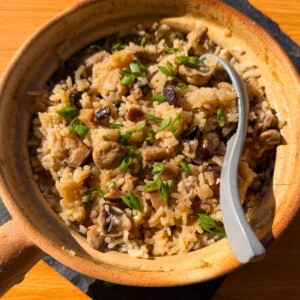 claypot chicken rice with mushroom in the cooking pot with spoon