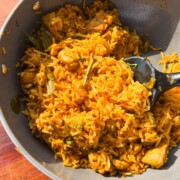 chicken pulao in the cooking pan with a ladle