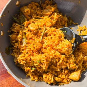 chicken pulao in the cooking pan with a ladle