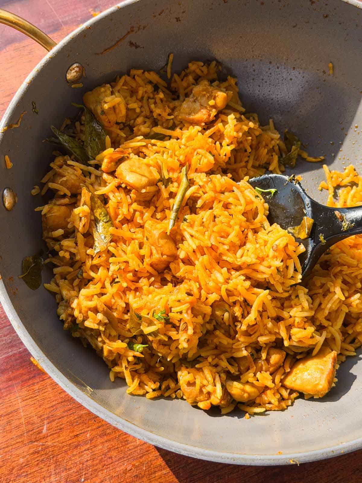 chicken pulao in the cooking pan with a ladle