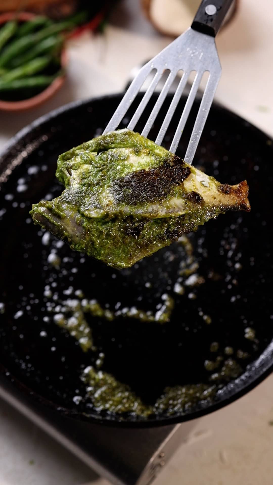 pomfret fry with green masala being fried on a tawa