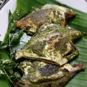 pomfret fry with green masala served on a plate of banana leaves
