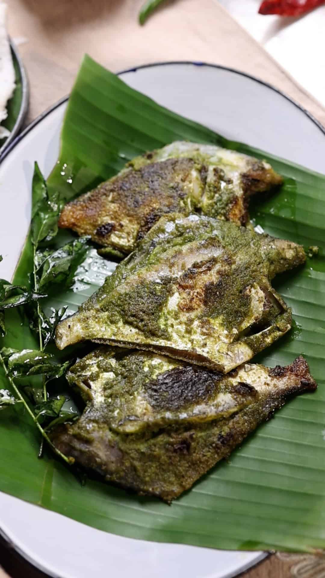 pomfret fry with green masala served on a plate of banana leaves