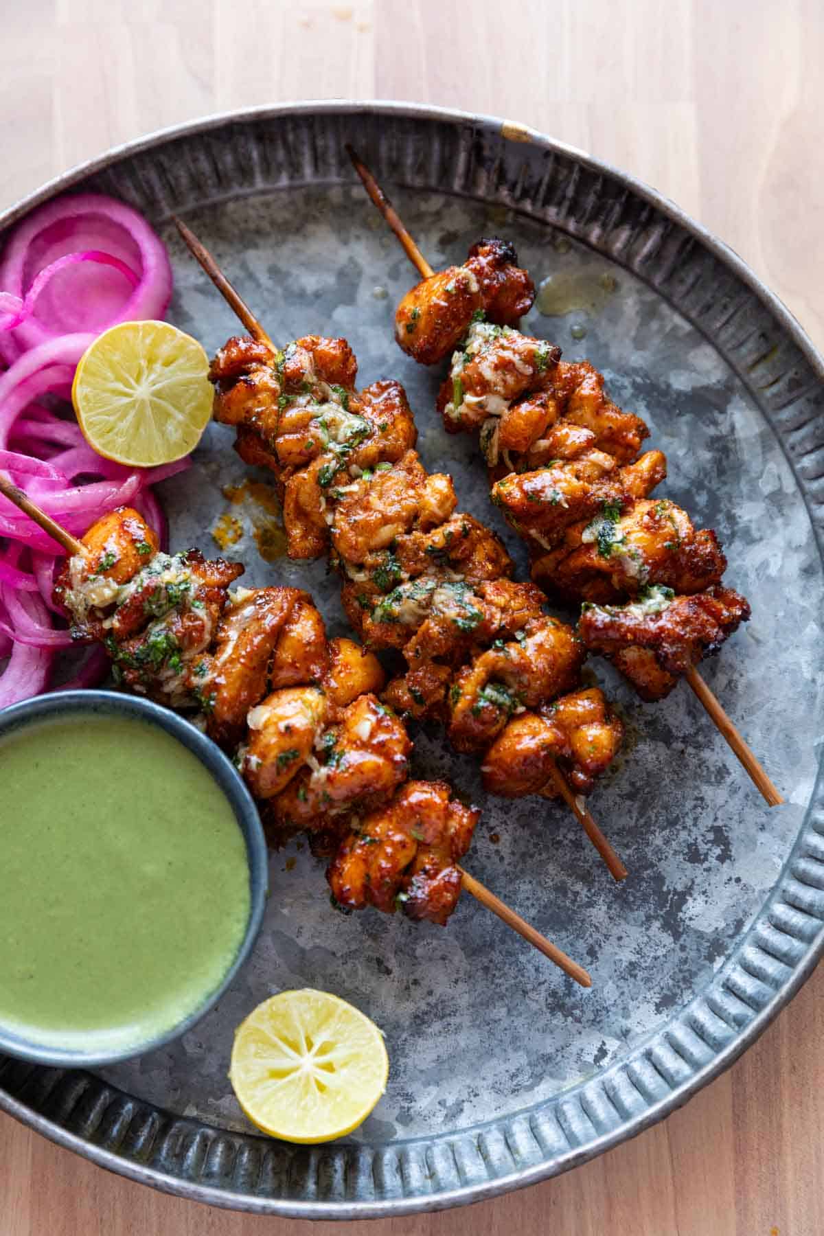 an image of achari chicken tikkas served in a plate with accompaniments