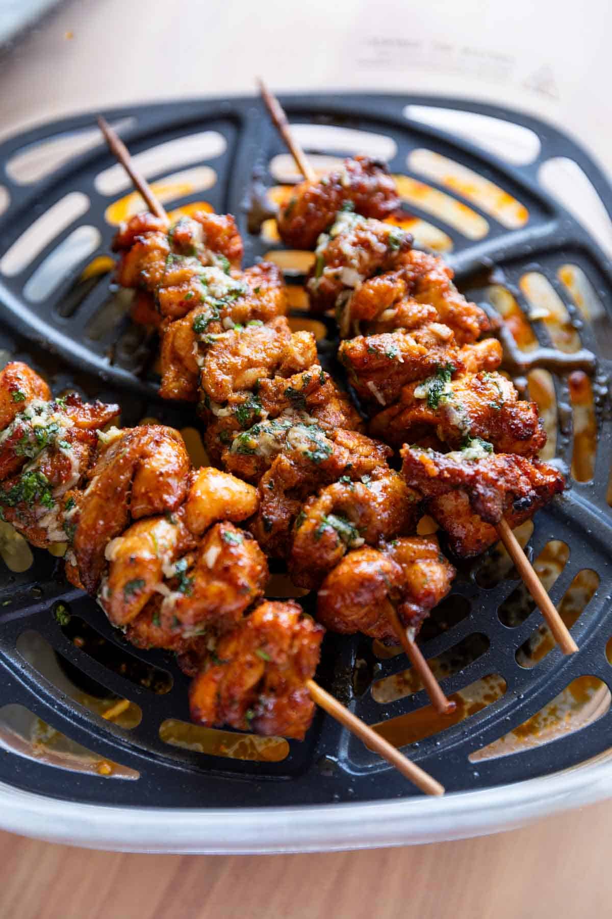 a close up image of achari chicken tikkas in the air fryer they were cooked in