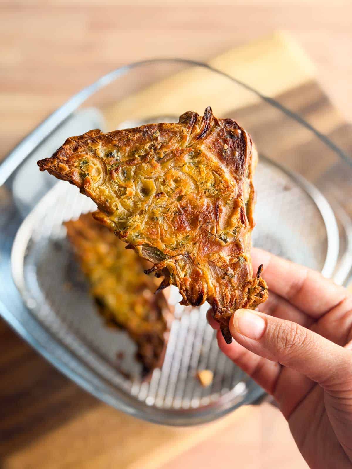 a person a holding up a piece of air fryer bread pakora to show it's crispy texture and color