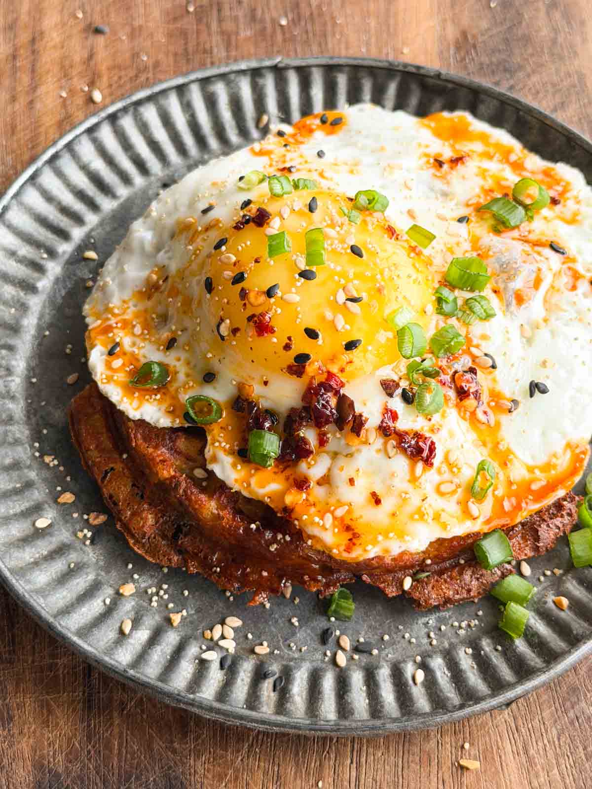 crispy potato waffle topped with a half fried egg and served on a plate