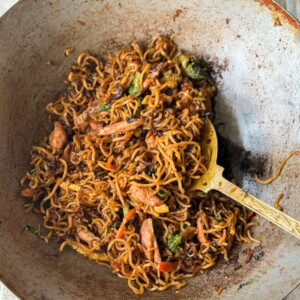 Thai drunken noodles in the wok that it was cooked in with a ladle